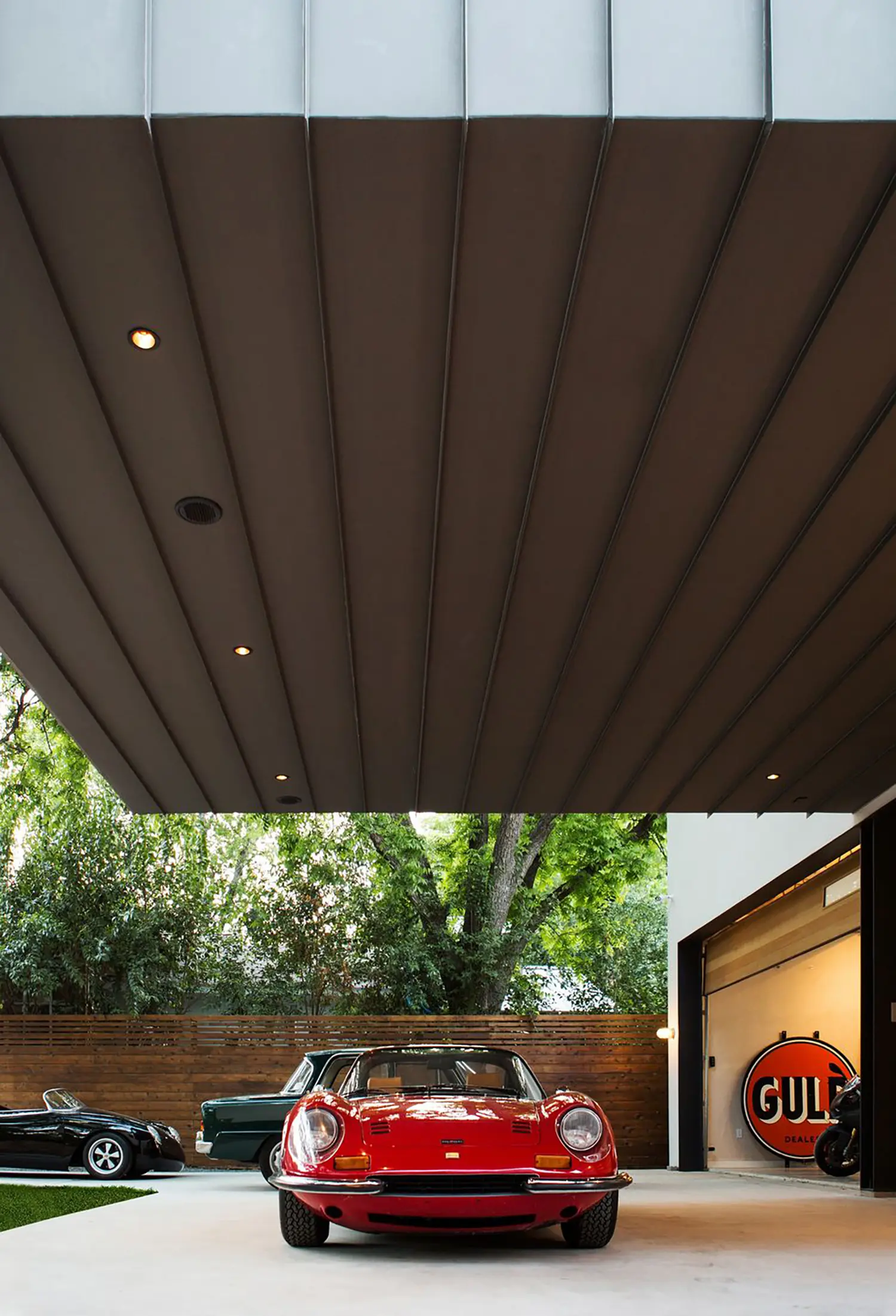 AutoHaus by Matt Fajkus Architecture, underside view of steel cantilever roofline with vintage red Ferrari Dino and Gulf sign