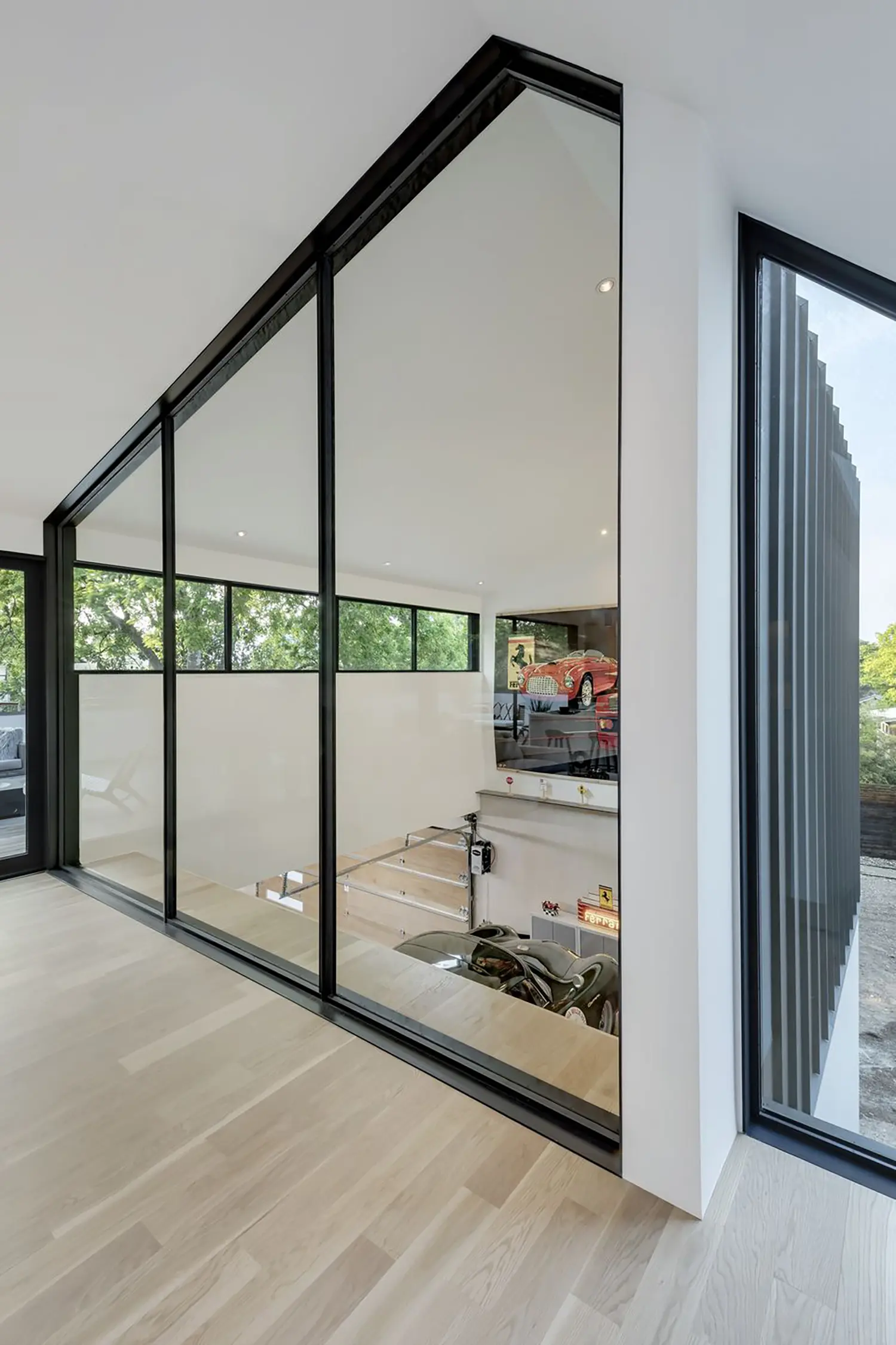 AutoHaus by Matt Fajkus Architecture, glazed stairwell interior overlooking garage floor and parked cars from above