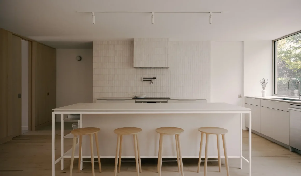 Minimalist kitchen with a large white island, light wood stools, and a pale subway tile backsplash extending to the ceiling.