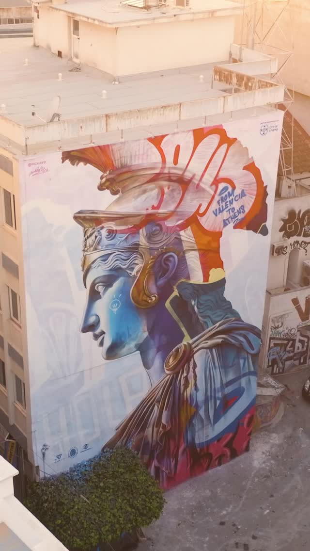 PichiAvo’s “An Offering to Athens” unfolds as a vertical dialogue between the weight of Hellenistic stone and the electric pulse of the street. As the perspective shifts, the mural reveals its true scale, positioning the goddess Athena as a vibrant, multi-layered presence within the city’s dense architectural fabric. This intervention transcends mere decoration, acting as a contemporary monument that bridges the gap between the foundational roots of Western art and the raw energy of modern Athens.  The ascent highlights a sophisticated mastery of perspective, where vibrant neon tags and classical shading converge to redefine the Mediterranean skyline. From this vantage point, the visual link to the nearby Acropolis becomes undeniable, proving that history is not a finished chapter but a continuous, evolving narrative breathing new life into the city’s ancient soul.  via #urdesignmag
artists @pichiavo 
video courtesy of PichiAvo  #PichiAvo #AnOfferingToAthens #AthensStreetArt #UrbanMythology