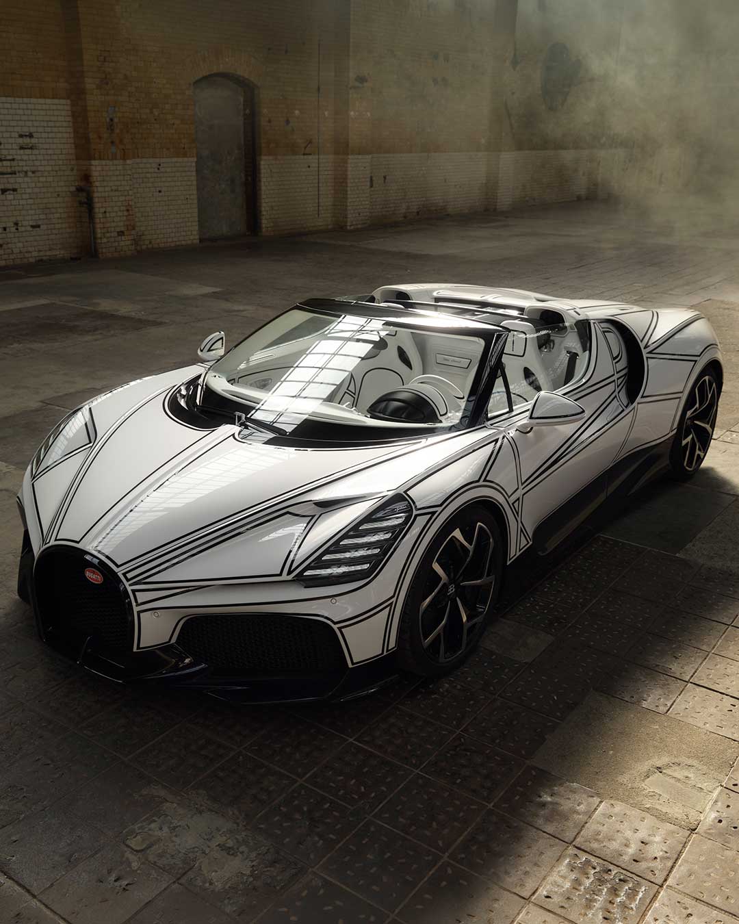 The black lines across this Bugatti W16 Mistral aren't decoration — they map the car's own invisible digital surface geometry, the NURBS network normally hidden inside the design software. Every line was masked and hand-painted directly onto the finished body, since no clay model existed to guide the process. Porcelain by KPM punctuates the exterior and interior alike, from the EB emblem to the gear-shifter shells — a material that shrinks by 17 percent when fired, meaning every piece has to be modeled to compensate before it's even made. Design: @bugatti
Porcelain: @kpmberlin urdesignmag.com — link in bio #Bugatti #WMistral #KPM #Porcelain #HypercarDesign