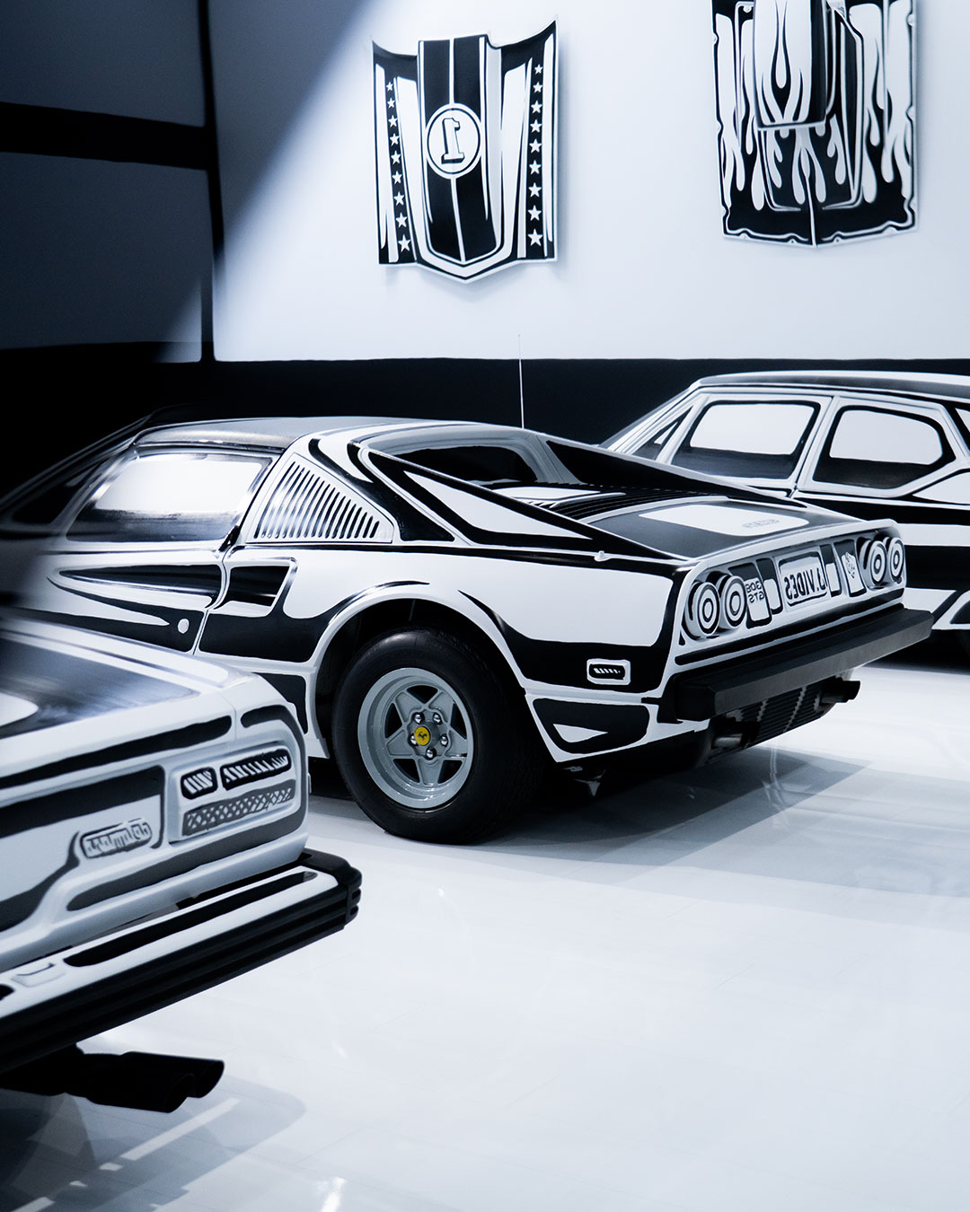 Five real cars, one gallery, and not a single surface left in three dimensions. Joshua Vides hand-painted the Petersen Automotive Museum's Armand Hammer Foundation Gallery into a monochrome mechanic's garage for Flat Out, applying his signature Reality to Idea technique — sharp black outlines on white — to the vehicles and to the room itself. Nine days of continuous painting went into the installation, with no room for correction once a line hit a full-size car. Even the wall text and the "No Parking" sign play along, flattened into the same illustrated language as everything else. artist: @joshuavides
images courtesy of @petersenmuseum urdesignmag.com — link in bio #JoshuaVides #FlatOut #PetersenMuseum #RealityToIdea #ArtInstallation
