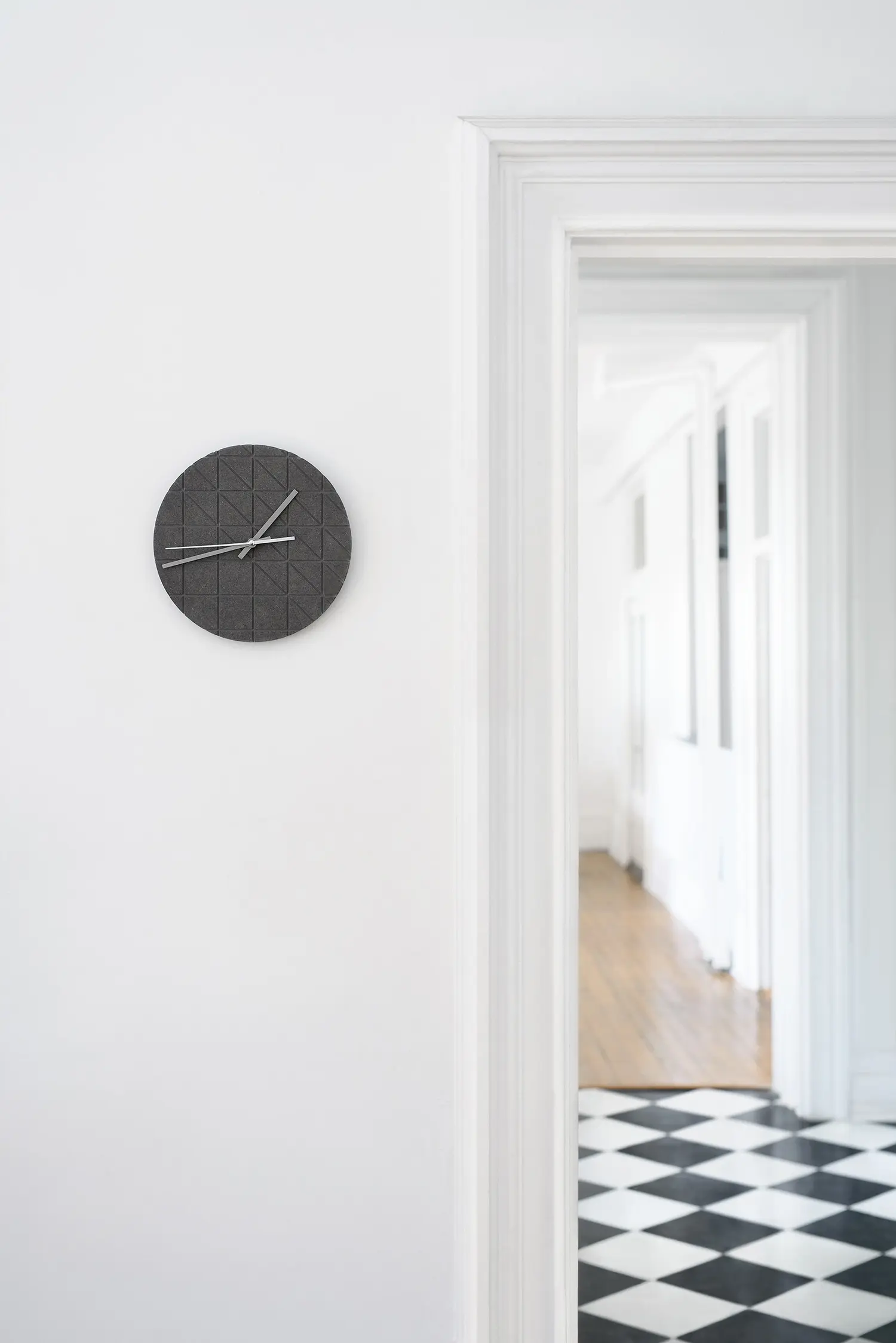 Gray wall clock hanging on a white wall