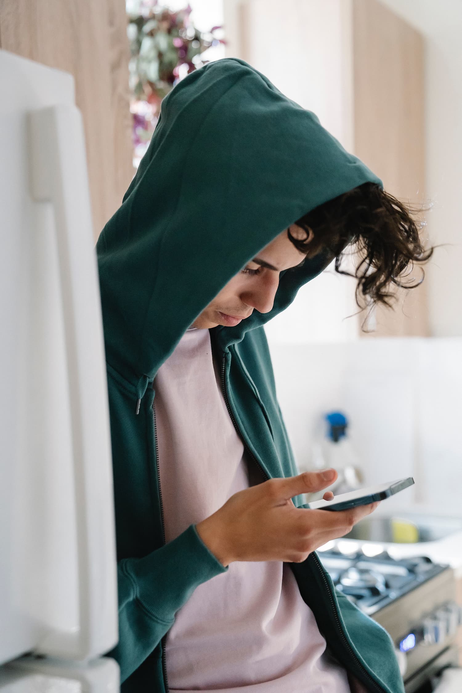 Boy wearing green hoodie while sending text messages