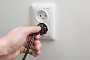 Person inserts a plug into a wall outlet