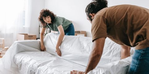 Couple Wrapping A Couch With White Cloth