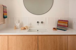 sink with cabinet and round mirror