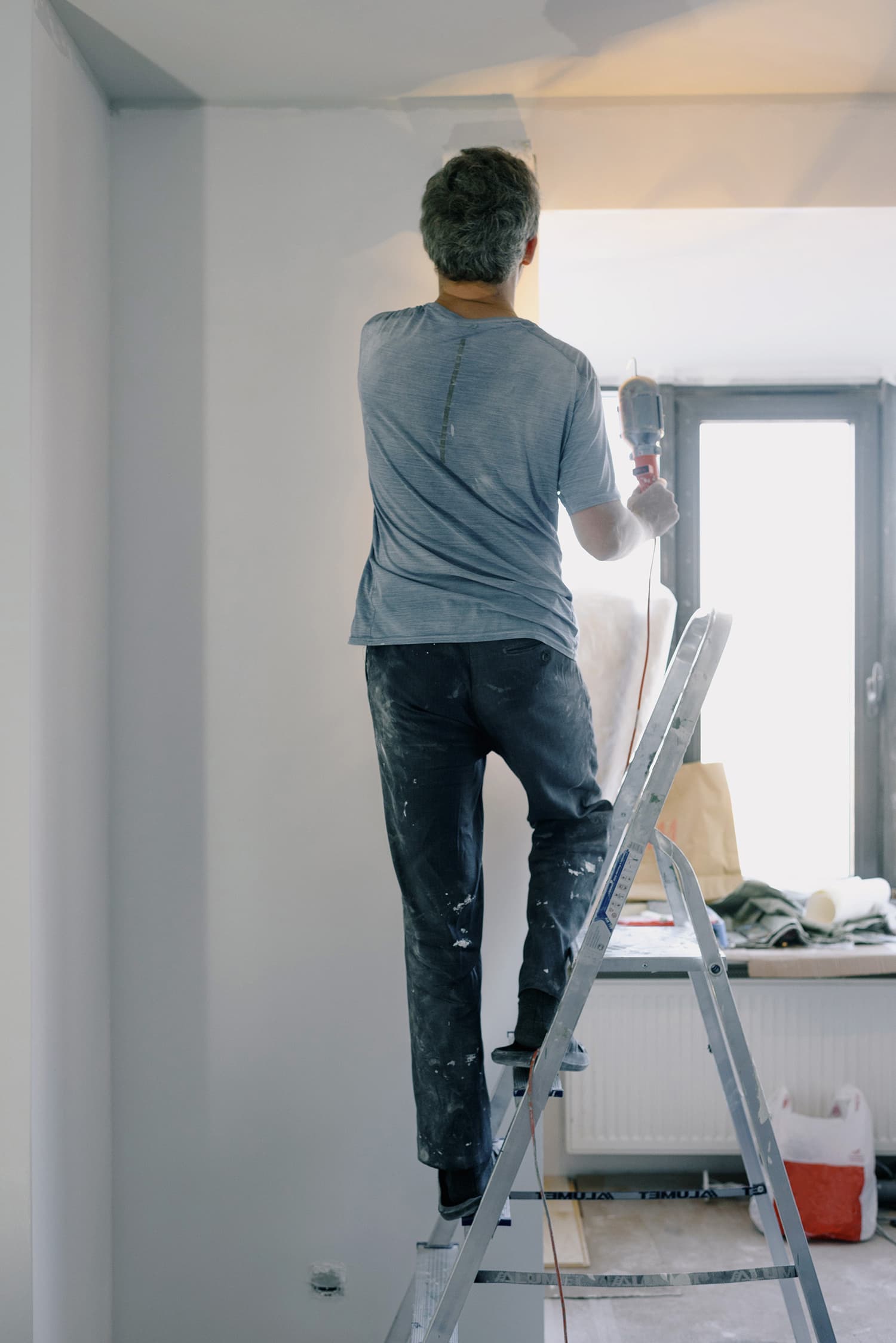 Man on a ladder paints a wall
