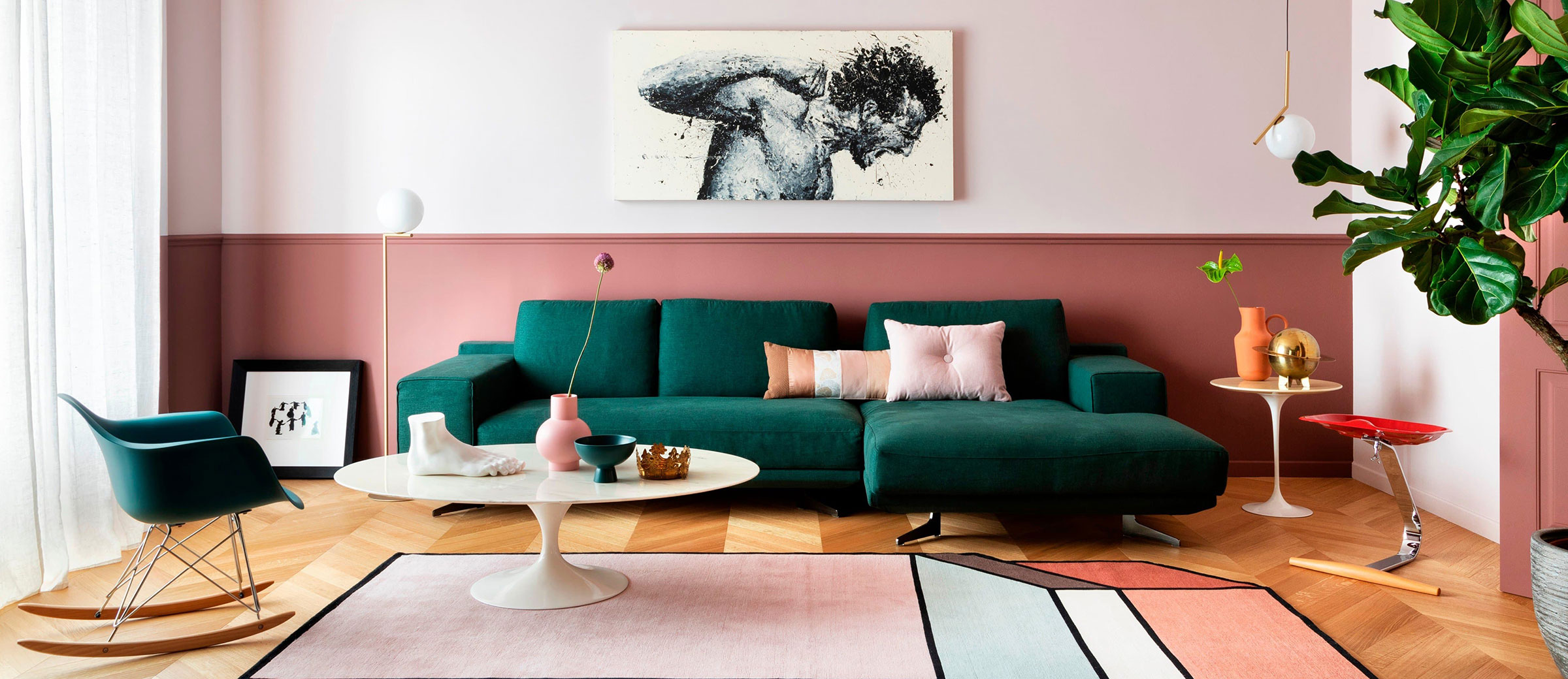 Living room with green sofa and pink walls and large wall art