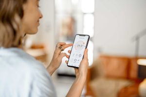 Woman with Smartphone with launched application for air temperature adjustment.
