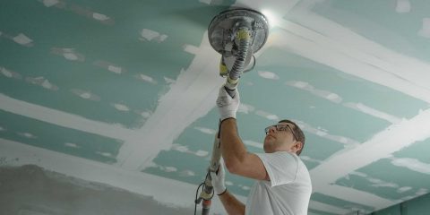 Worker removes popcorn ceiling with sander
