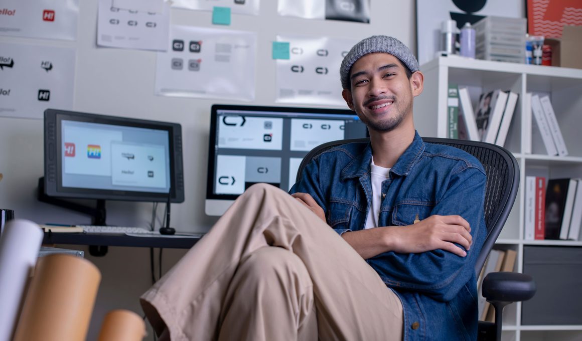 Portrait of Asian man designer sitting and smiling while looking at camera