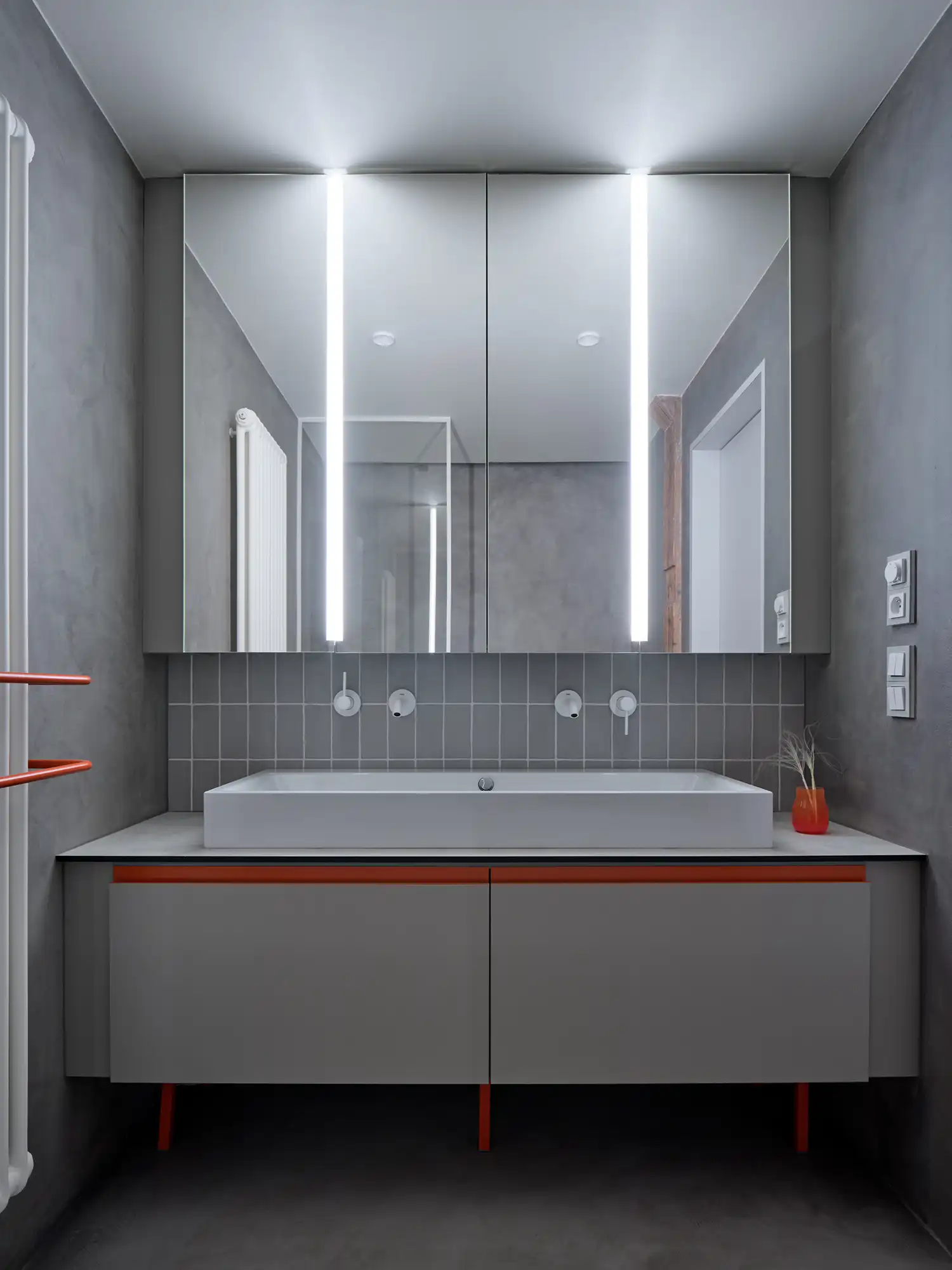 Sleek bathroom in the Arbes Square attic renovation, with matte steel fixtures, pale terrazzo tiles, and a skylight above the shower.