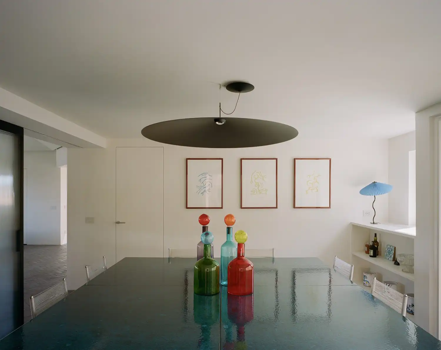 PAROS Architettura Redefines Roman Elegance with Casa ANCE’s Hybrid Guesthouse-Meeting SpaceIn Rome’s historic neighborhood near Villa Torlonia, PAROS architettura has transformed a disjointed early 20th-century penthouse into Casa ANCE - a sophisticated hybrid space that effortlessly blends residential comfort with professional functionality. The project, commissioned by Italy’s national association of building companies, reimagines the 140-square-meter apartment and its 160-square-meter terrace as both a guest residence and meeting venue, creating a compelling case study in adaptive reuse. The original layout presented significant challenges - three separate units with a complex pitched roof structure and varying ceiling heights created a fragmented interior. PAROS architettura’s solution was to completely rework the spatial organization, establishing a clear distinction between public reception areas and private zones while preserving the building’s historic character. The design team saw opportunity in the existing architectural constraints, using them to inform a thoughtful, contemporary intervention. At the heart of the renovation is a stunning open-plan public area where the original roof beams remain exposed, creating visual drama and a sense of continuity. A sliding iron-and-glass partition system provides flexible division of space, allowing the dining and meeting area to be either incorporated into the main flow or closed off for private functions. This innovative approach maintains spatial fluidity while accommodating different uses. The material palette speaks to the building’s industrial heritage while achieving modern elegance. Raw stone surfaces, microcement floors, and custom-designed wood-and-iron furnishings create a tactile, minimalist aesthetic. PAROS architettura’s careful selection of natural materials reflects both the client’s identity in the construction industry and Rome’s architectural legacy, resulting in spaces that feel simultaneously contemporary and timeless.