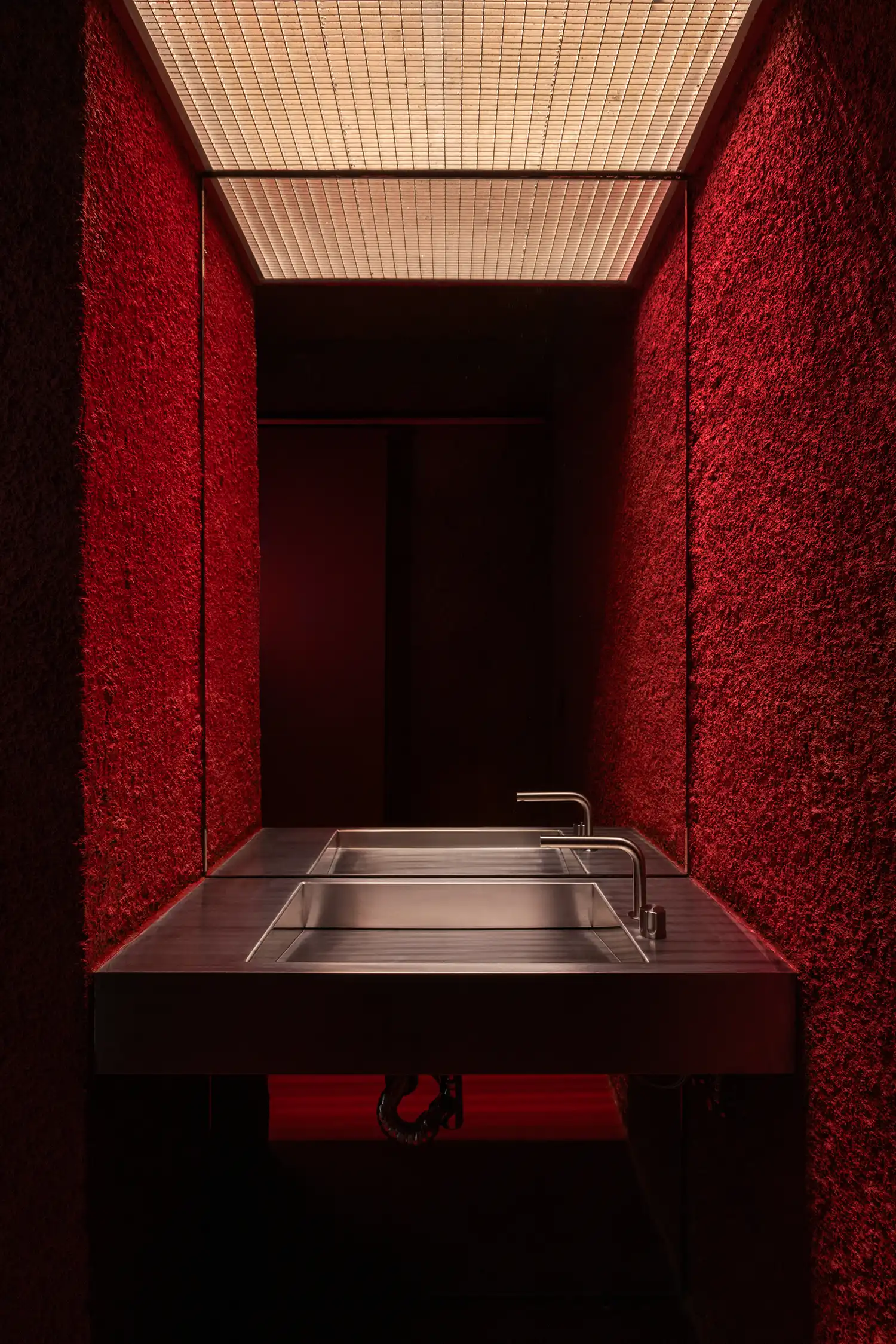 Bold red bathroom with rough finishes at L'ALTRO Milan – Sagoma Studio’s dramatic contrast in design
