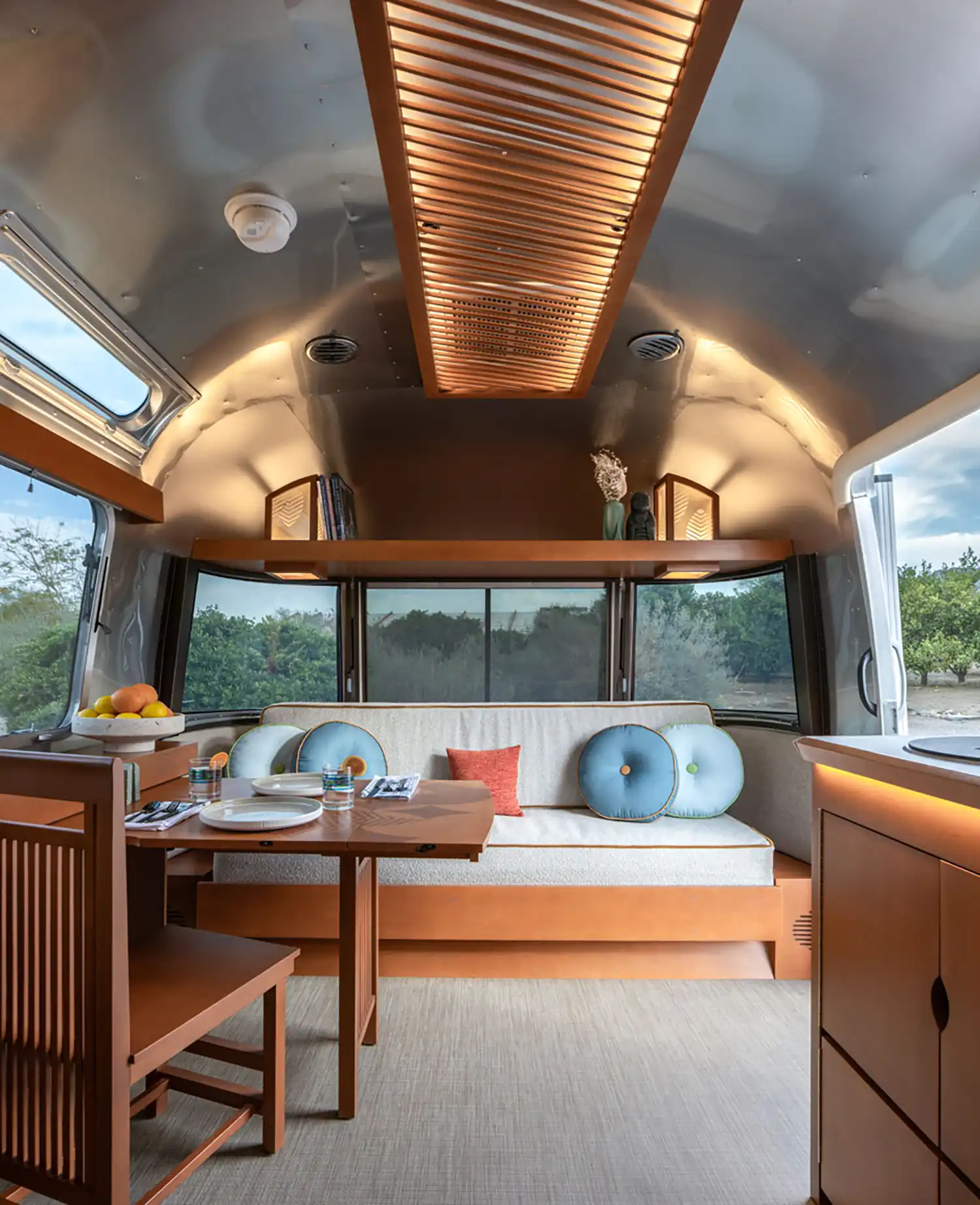 Interior of the Frank Lloyd Wright Airstream trailer showcasing warm wood finishes, built-in furniture, and mid-century modern design inspired by Usonian architecture.