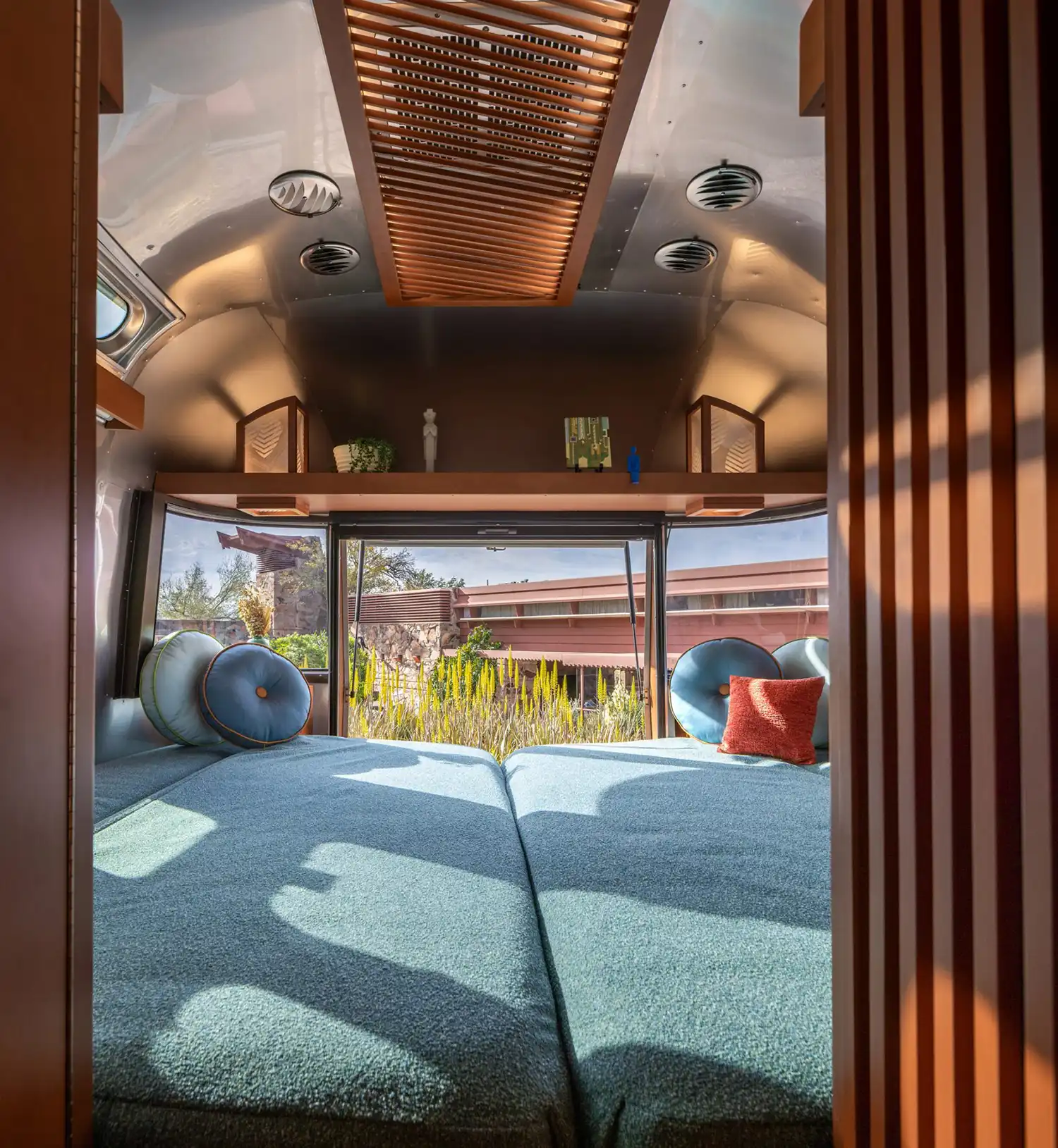 Frank Lloyd Wright Foundation’s Airstream collaboration interior bedroom with queen-sized bed, integrated shelving, and organic material textures.