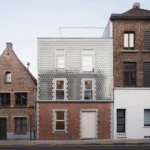 Glass brick house facade in Ghent, Belgium: Sustainable CLT home on narrow lot with double-skin insulation & historic context.