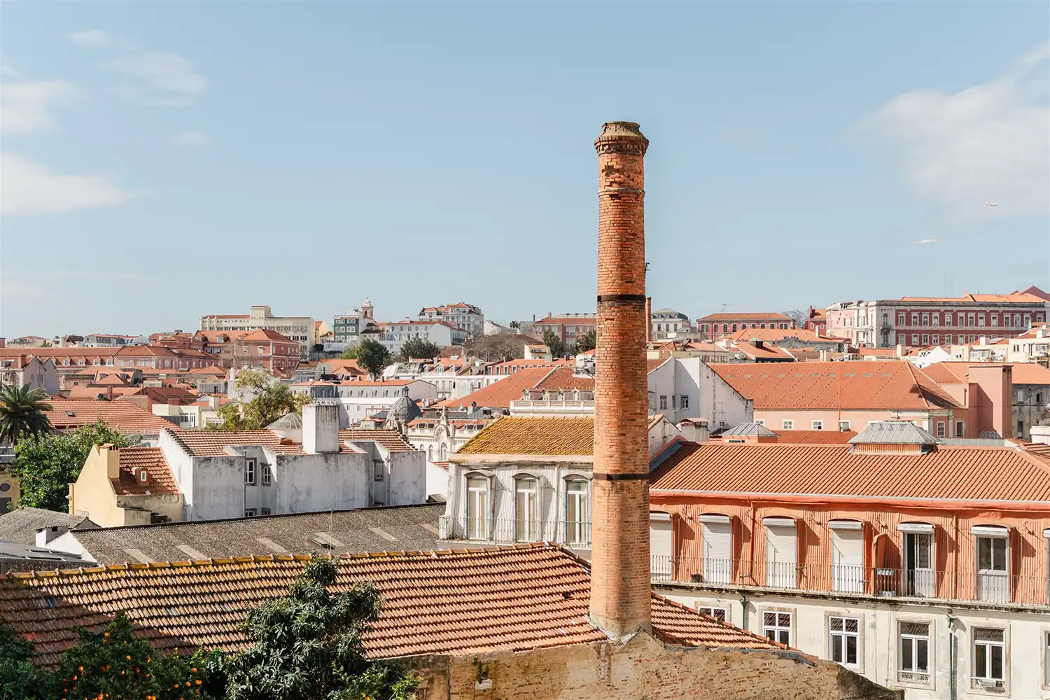 Sunlit private terrace at Stay Intendente, Lisbon, with outdoor seating and views of the vibrant Intendente neighborhood