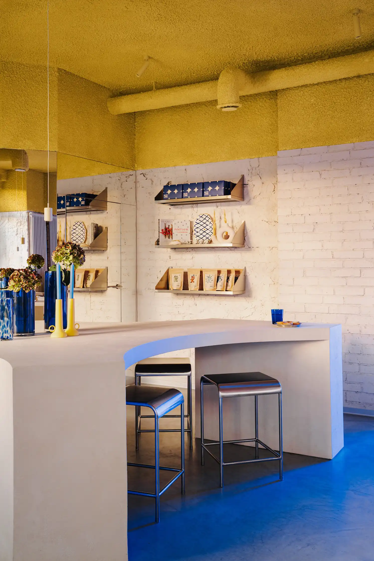 Yellow spray foam ceiling at Pastelowe patisserie, creating irregular texture like ocean foam. Designed by Znamy Sie to evoke Portuguese sunlight in Warsaw.