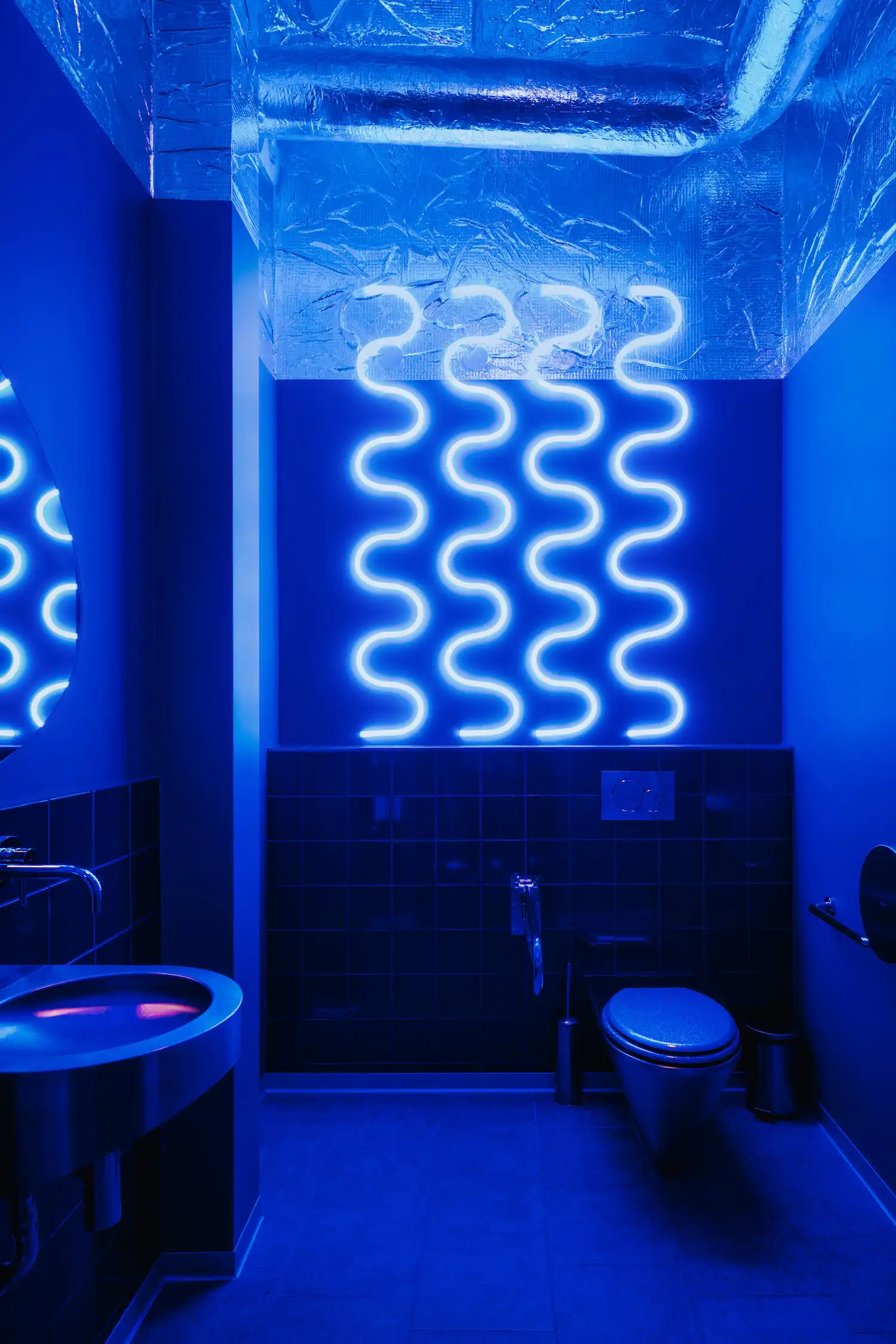 Coastal-inspired bathroom at Pastelowe Warsaw, featuring organic curves and marine blue accents. Designed by Znamy Sie to mirror the patisserie’s Portuguese surf theme with textured walls and wave-like details.