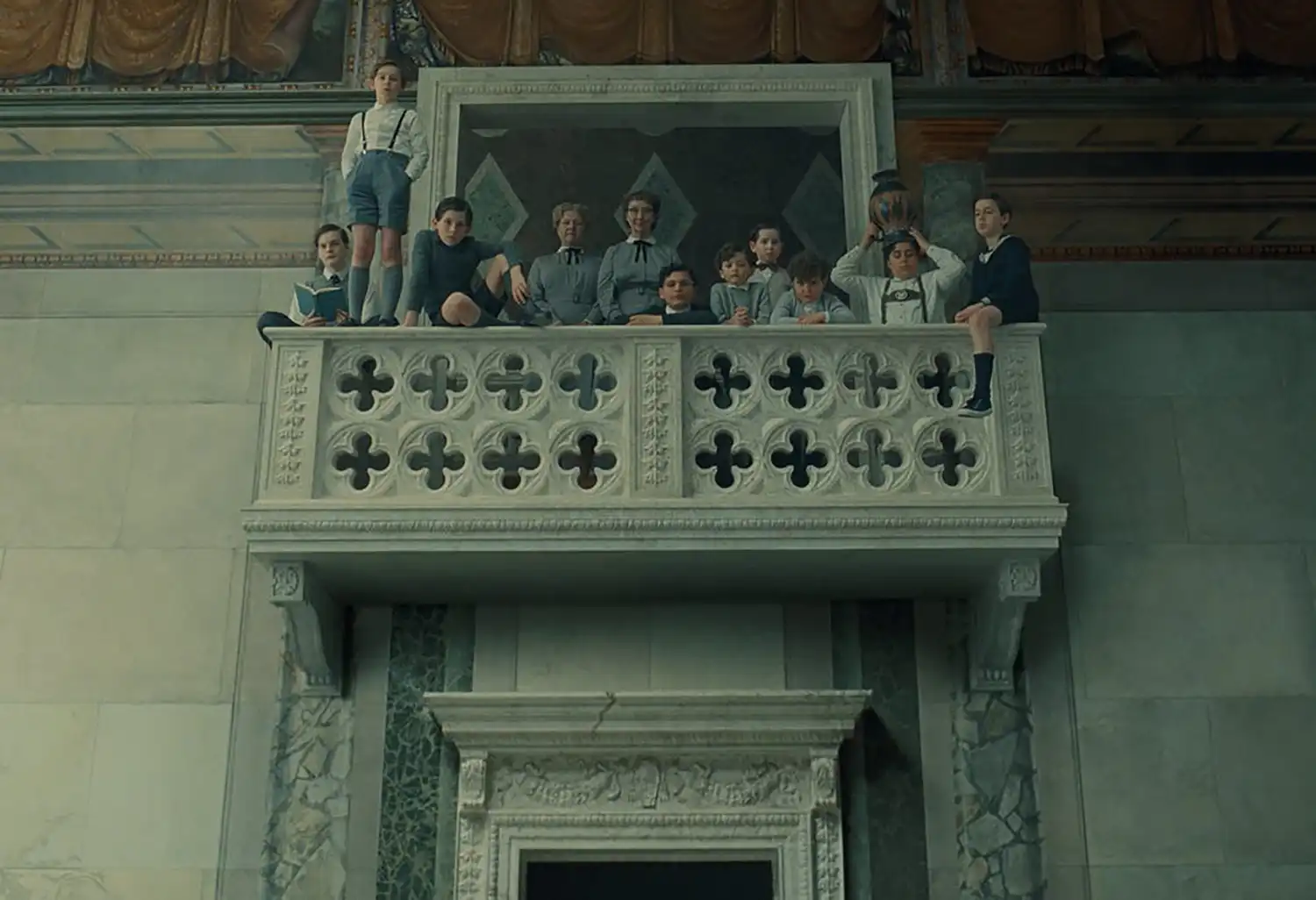 Cinematic still from "The Phoenician Scheme" showcasing retro-futuristic architecture and detailed production design.