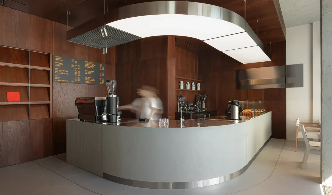 Curved wood veneer bar counter at Biblioteka Coffee Moscow by KIDZ Studio, blending metallic accents and warm lighting