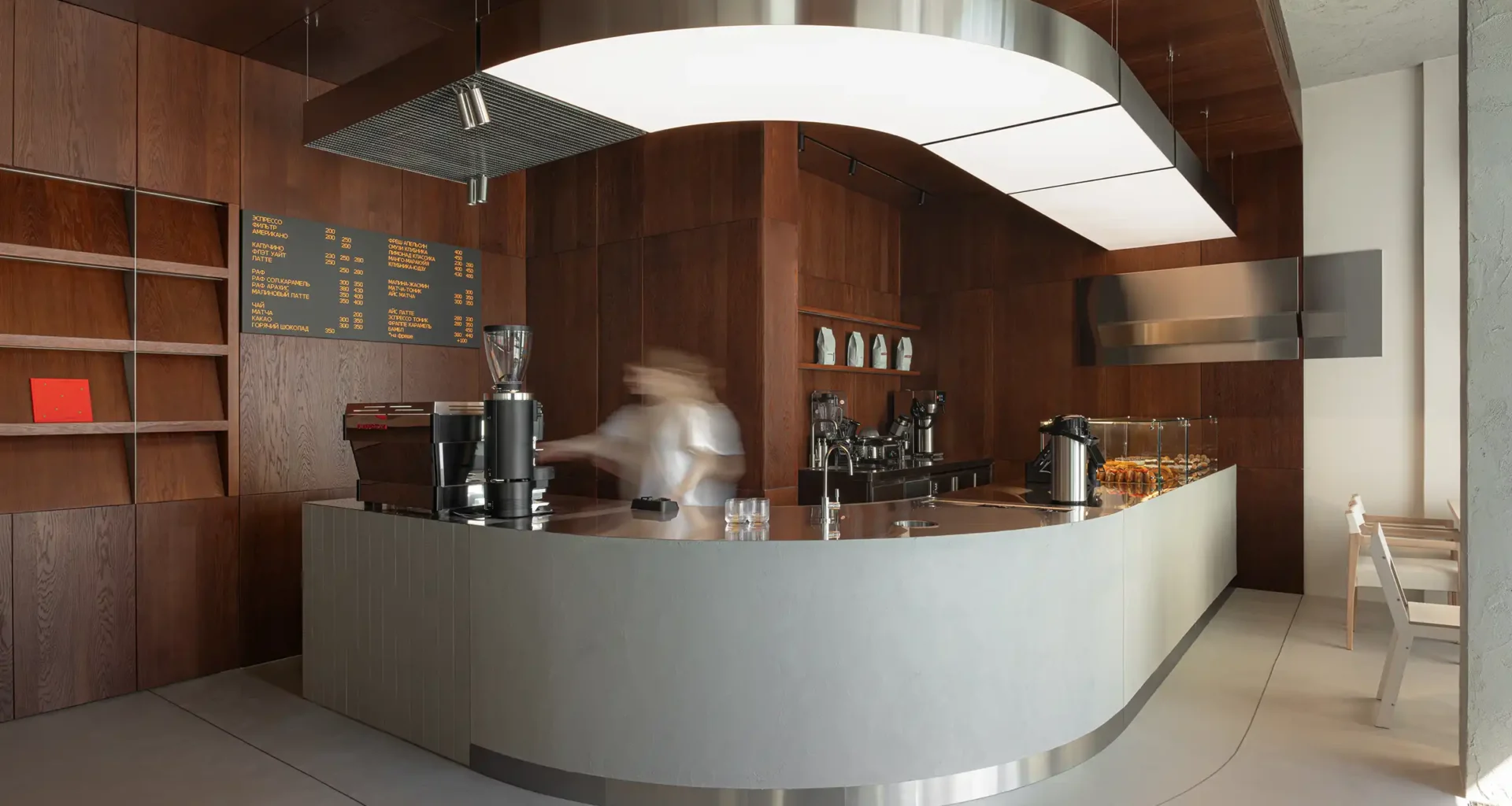 Curved wood veneer bar counter at Biblioteka Coffee Moscow by KIDZ Studio, blending metallic accents and warm lighting