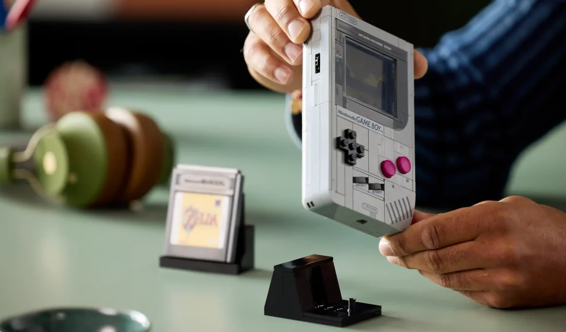 An adult building the LEGO Nintendo Game Boy 1:1 model kit (72046) with +Control Pad, A/B buttons & interchangeable Zelda/Mario cartridges