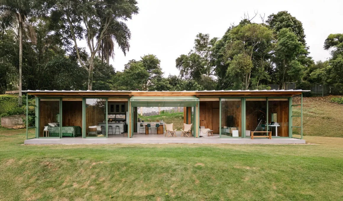 Front view of Nitsche Arquitetos’ House in Piedade showing cross-laminated timber volumes, covered veranda, and translucent tile roof in São Paulo countryside.