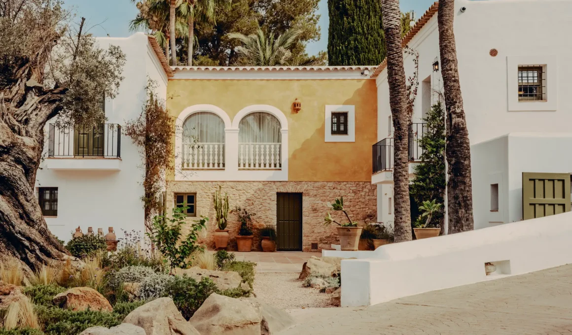 Soho Farmhouse Ibiza exterior curb view: white Spanish farmhouse nestled in olive grove, Santa Gertrudis, Balearic architecture