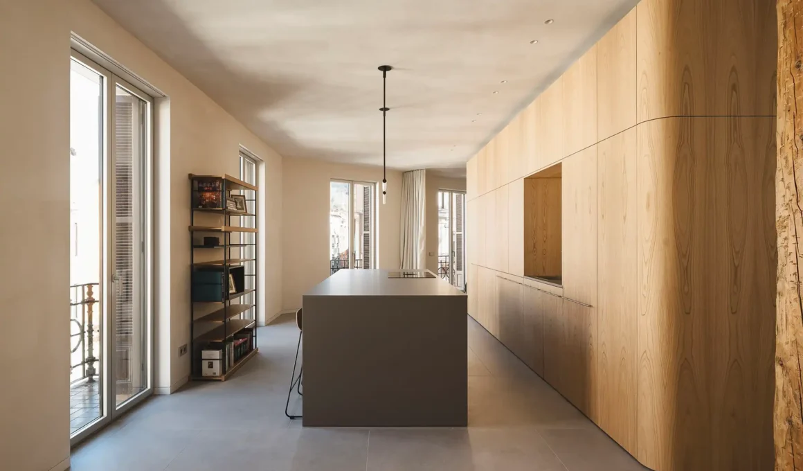 Curved chestnut wood core anchors kitchen in Verne Heros House Bilbao refurbishment, spatial efficiency & natural light.