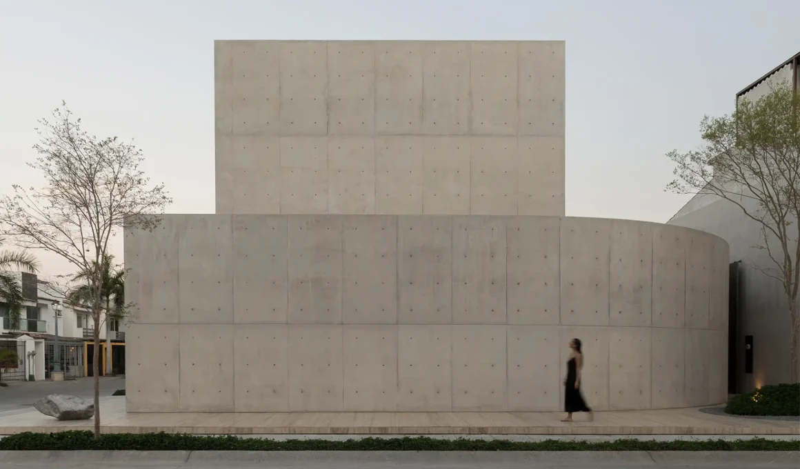 Exterior view of Casa Tao residential house in Puerto Vallarta by HW Studio, featuring a curved concrete wall and garden from street level.