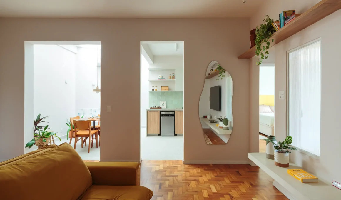 Renovated open-plan living area in DD Apartment, São Paulo, by Estúdio Maré, featuring a glass-covered courtyard, integrated kitchen, and custom cabinetry.