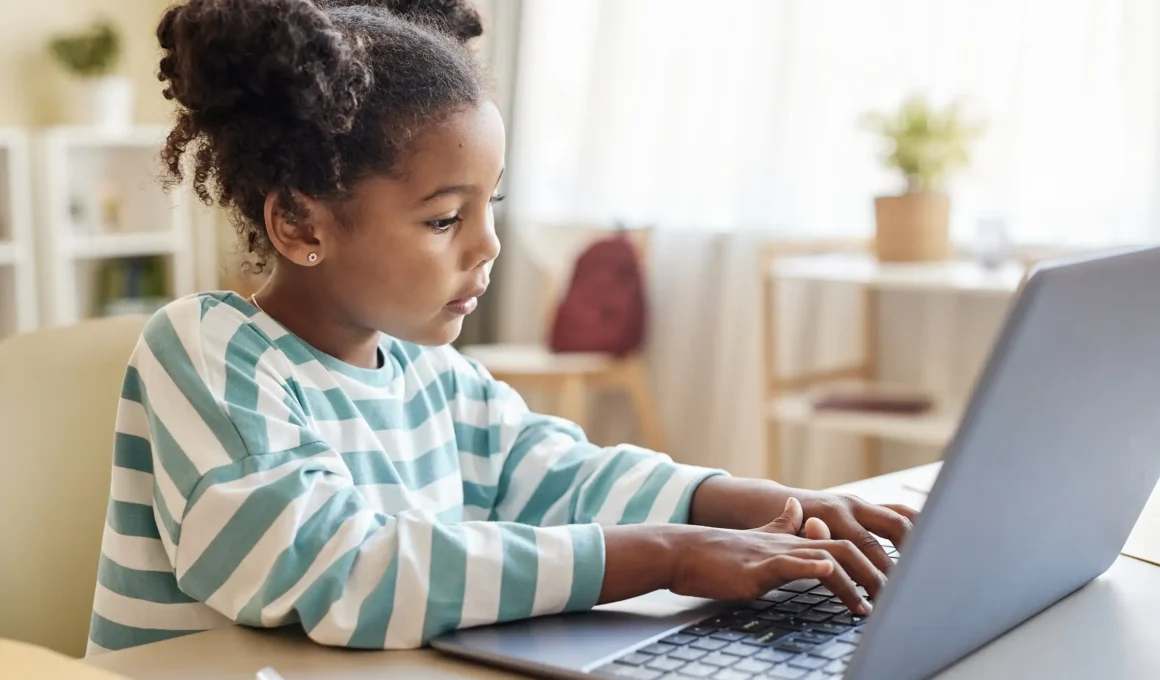 A young Black girl student using Study Bunny focus timer app on her Microsoft laptop to study productively with her virtual pet bunny.