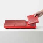 Hotcake modular magnetic speaker system showing wearable wrist strap and wireless daisy-chaining for collaborative music play.
