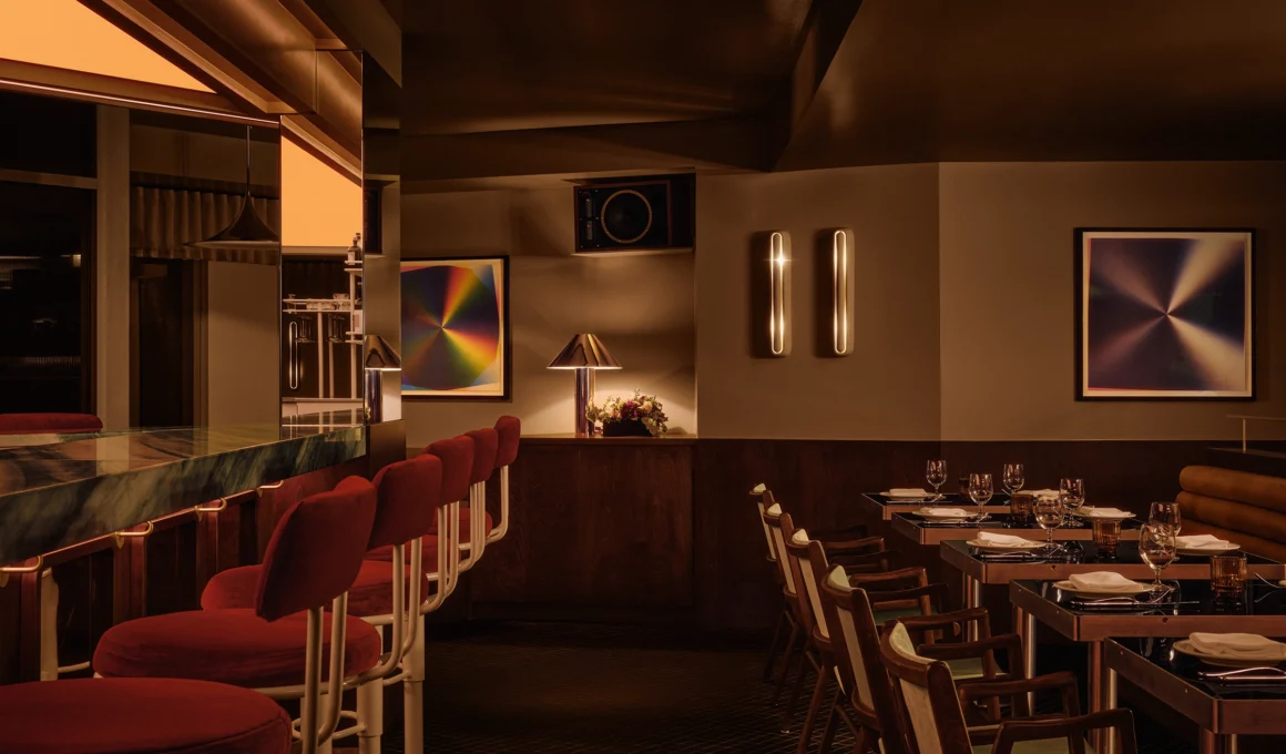 Limousine restaurant interior design by IVY Studio showing the central green marble bar under an amber diamond lightbox with red velvet stools in Saint-Lambert, Québec.
