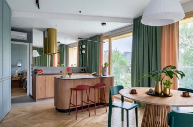 Renter-friendly living room with a modern grey armchair, lush indoor plants in design pots, and removable decor on a neutral wall.