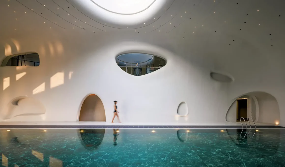 Wutopia Lab's The Rock Cloud Center cantilevered pebble-shaped mountain hotel with outdoor hot spring pools and view of Great Wall in Zunhua, China.