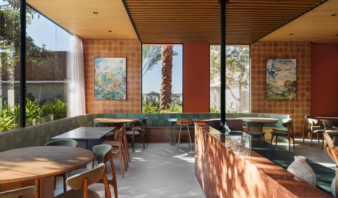 Elegant contemporary interior of Cozze Ristorante in Brasília by Hersen Mendes Arquitetura, showcasing curved balcony, organic architecture, and integration with a native tree.