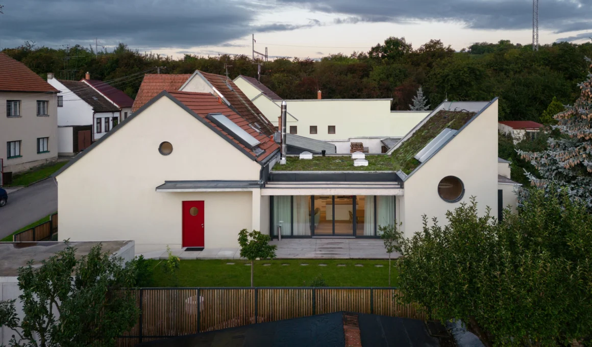 Aerial view of the renovated Family House Křenovice in South Moravia, showing the original structure with a new garden extension and bedroom pavilion connected by a terrace, designed by ika.architekti.
