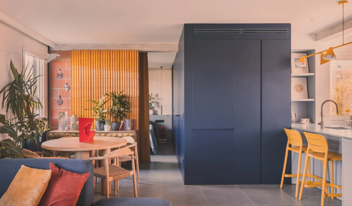 Vibrant living area OOIIO Architecture House 64 Madrid small apartment renovation interior design flexible open layout blue sofa metallic wall.