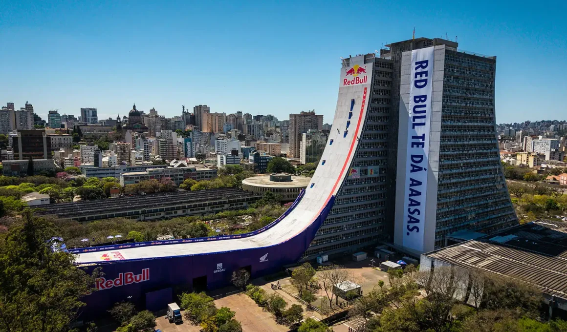 A skateboarder descends the massive vertical curve of the Red Bull and Prada collaborative skate ramp installed on the 16-story brutalist facade of the Porto Alegre Administrative Center skyscraper in Brazil.