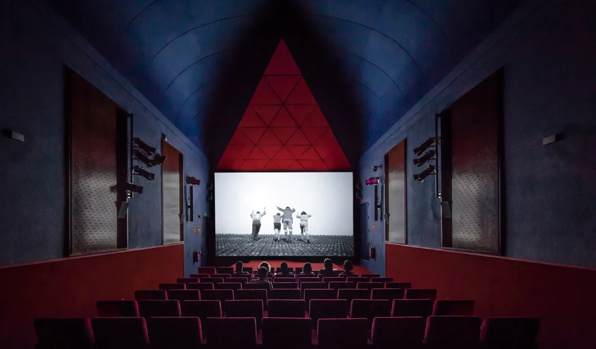 Bach Arquitectes Reina Sofía Cinema interior. View of the red seating, blue vaulted ceiling, and geometric acoustic screen in Madrid.