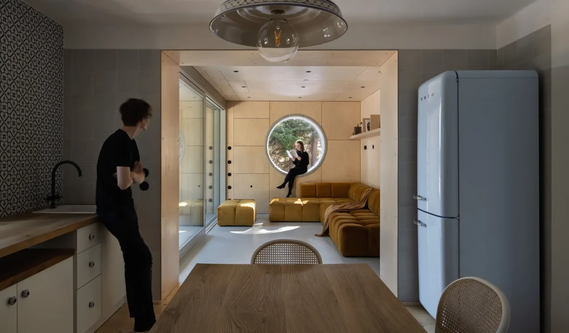 Borová Lada Cottage interior by Studio Plyš showcasing the seamless modern living and kitchen space, featuring exposed concrete, custom furniture, and large-format glazing.