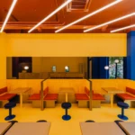 Bruzkus Greenberg FLIP-N-FRY Berlin restaurant interior design with bold yellow colour-blocking, stainless steel banquettes, and terra-cotta accents.