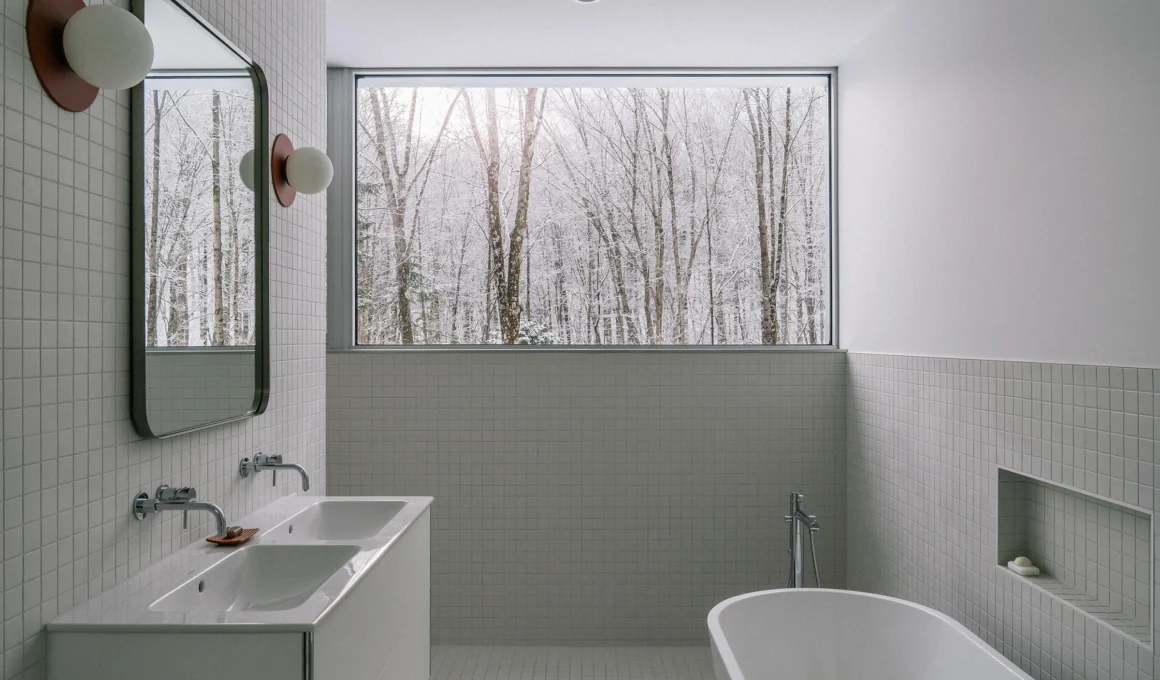 Luxury bathroom design with stunning forest view at Chalet du ruisseau by EM Architecture in Potton, Quebec