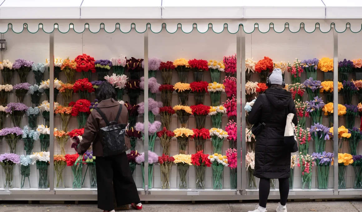 Alt Text: Cj Hendry permanent Flower Shop in SoHo New York, displaying rows of colorful collectible plush flowers behind a sleek storefront facade.