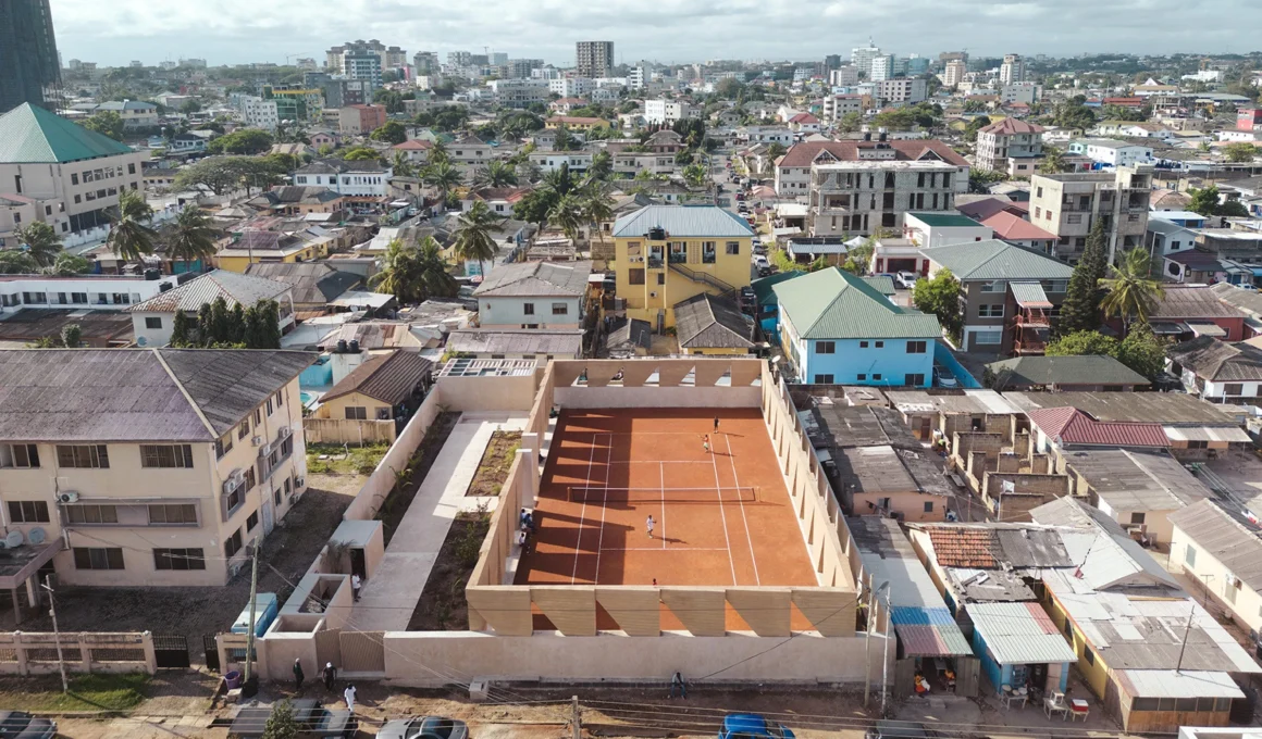 Precast rammed earth walls enclosing the Backyard Community Club tennis court in Accra, Ghana, designed by DeRoche Projects.