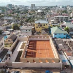 Precast rammed earth walls enclosing the Backyard Community Club tennis court in Accra, Ghana, designed by DeRoche Projects.